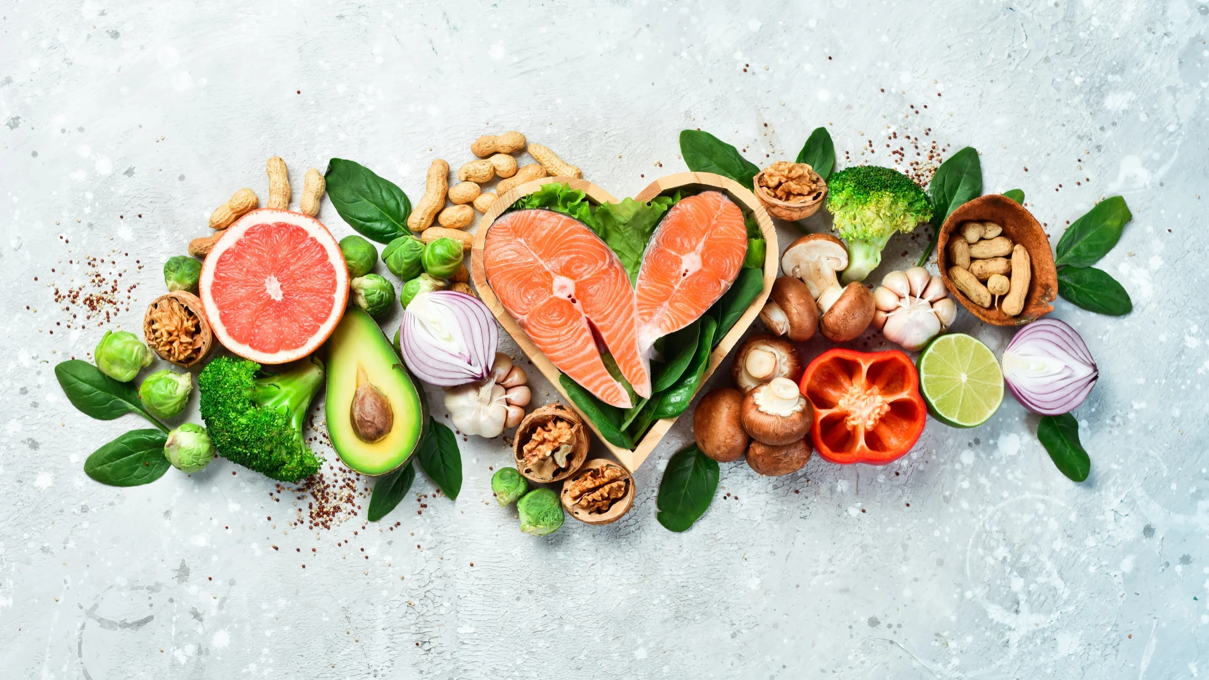 Alimentos saludables: salmón en un cuenco con forma de corazón, aguacate, pomelo, frutos secos, setas y verduras