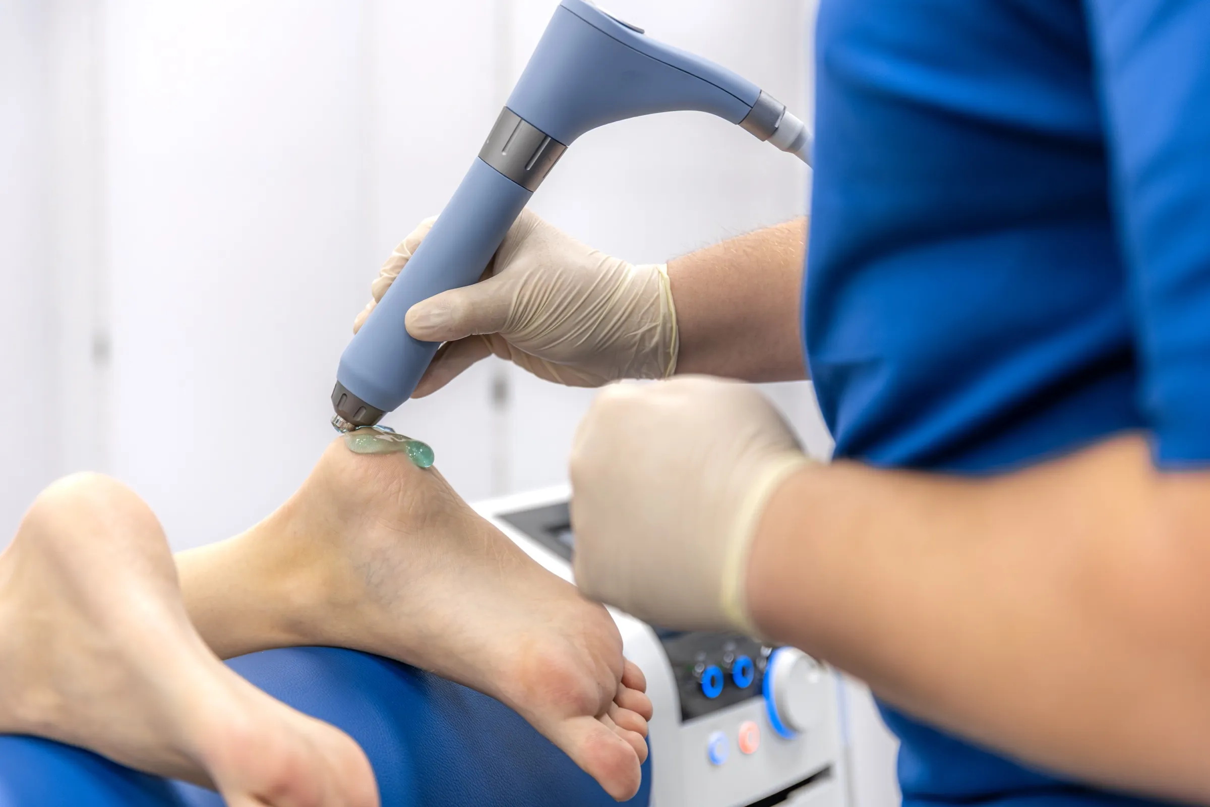 Fisioterapeuta aplicando ondas de choque en el talón de un paciente